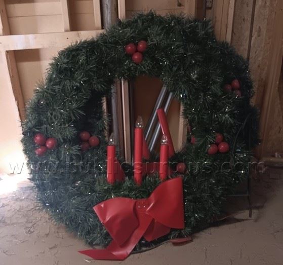 Photo of a 4' green decorative wreath with red berries and candles